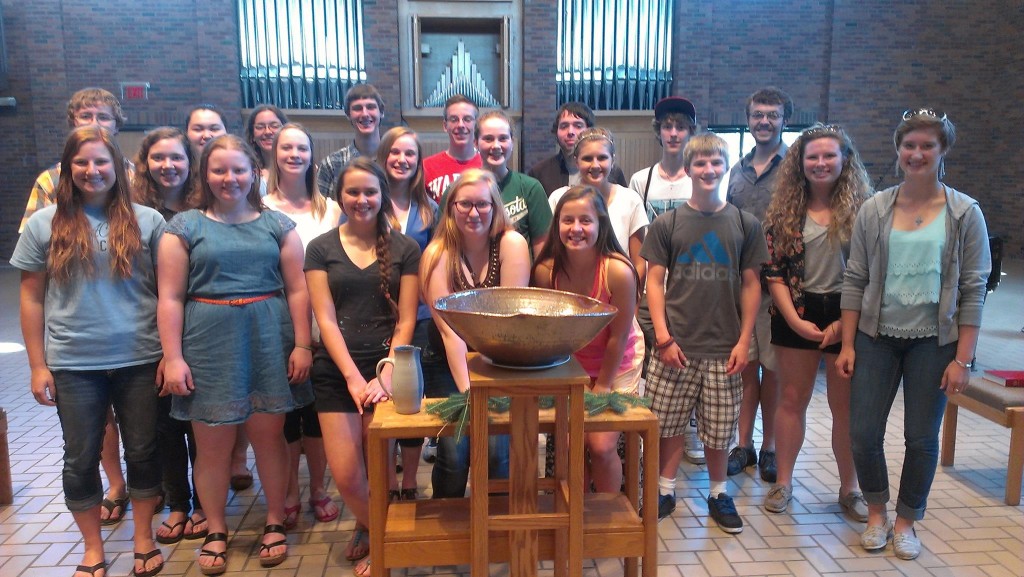 participants of the augsburg youth theology gather around a font posing for the camera